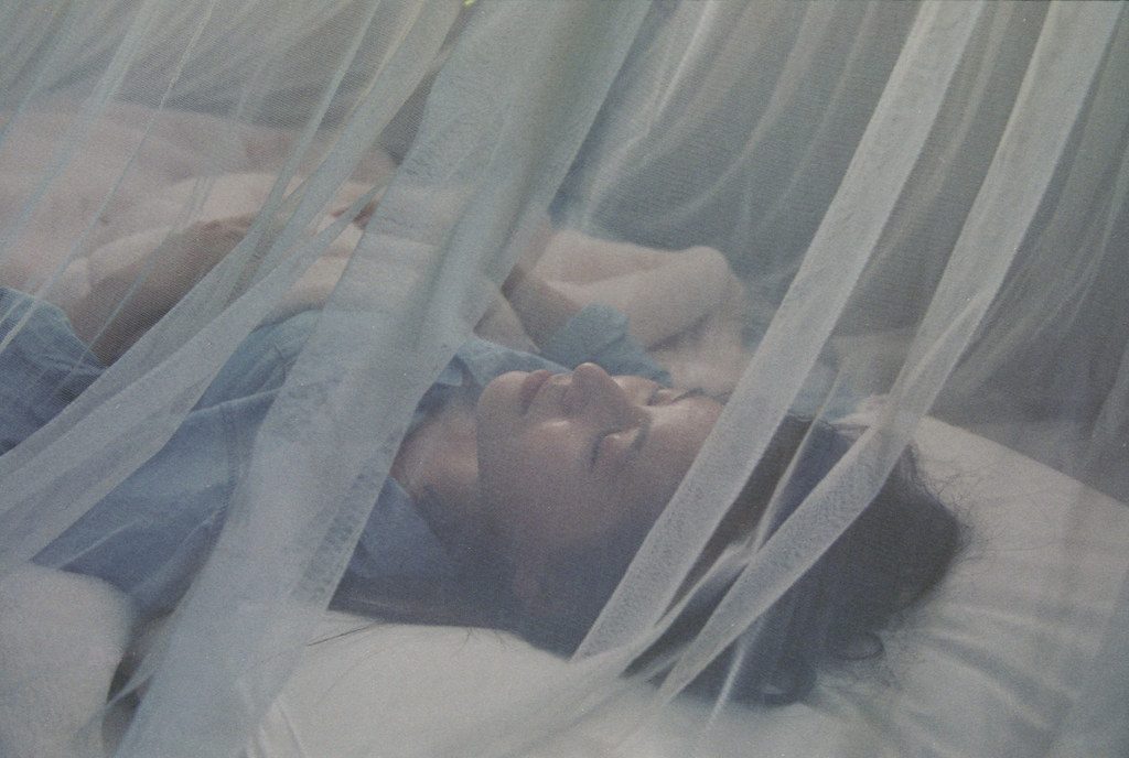 A person sleeping under a mosquito net