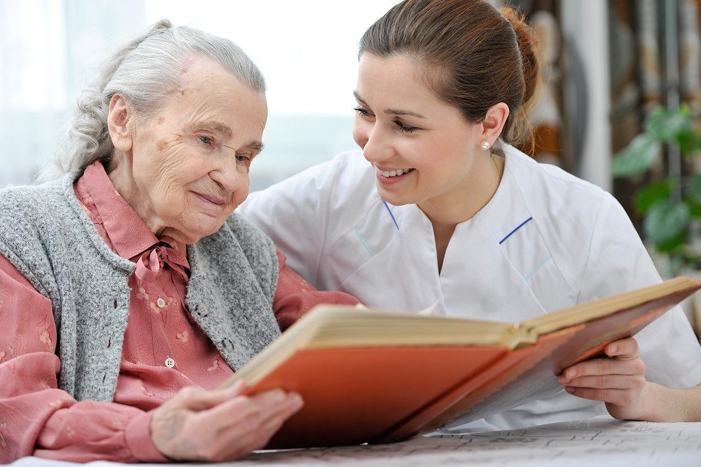 A caregiver reading a book with an older woman