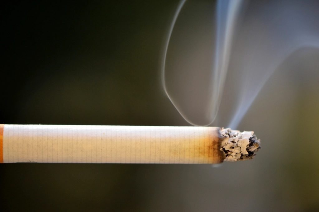 A lit cigarette with rising smoke