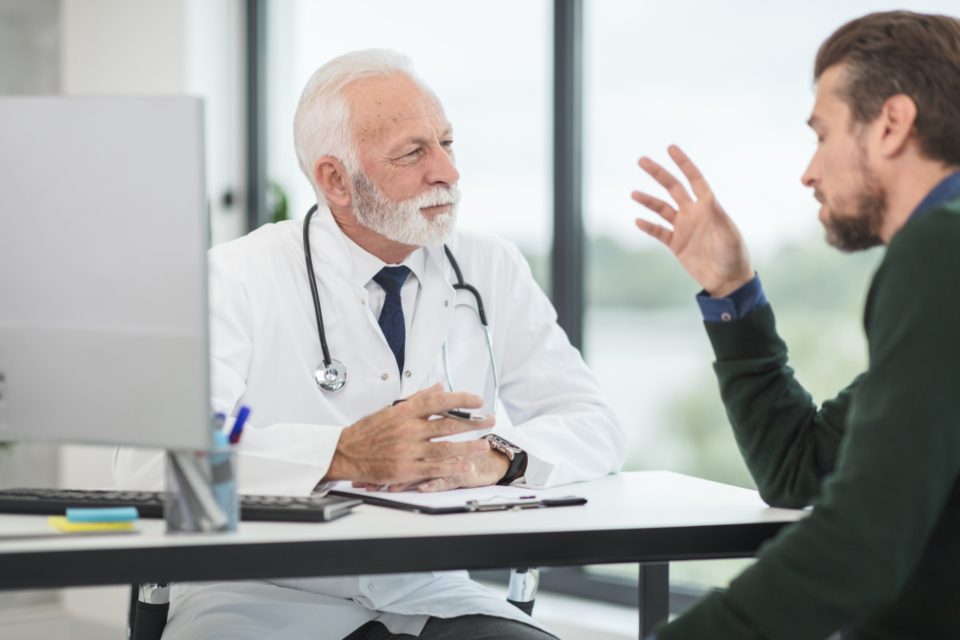 A doctor talking with a patient across a desk