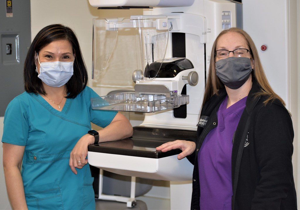 Two technologists beside a mammography machine