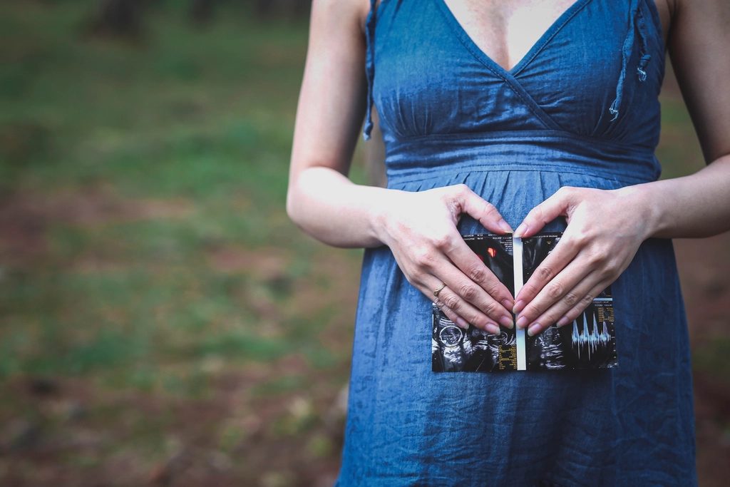 A pregnant woman holding an ultrasound picture