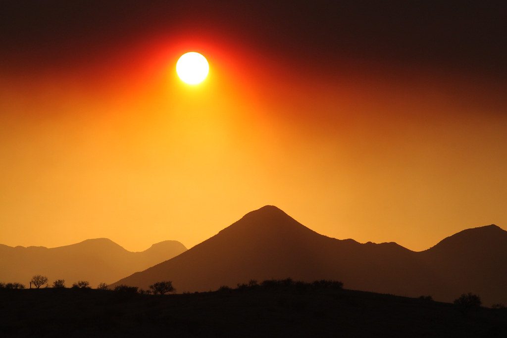 An orange sun seen through wildfire smoke